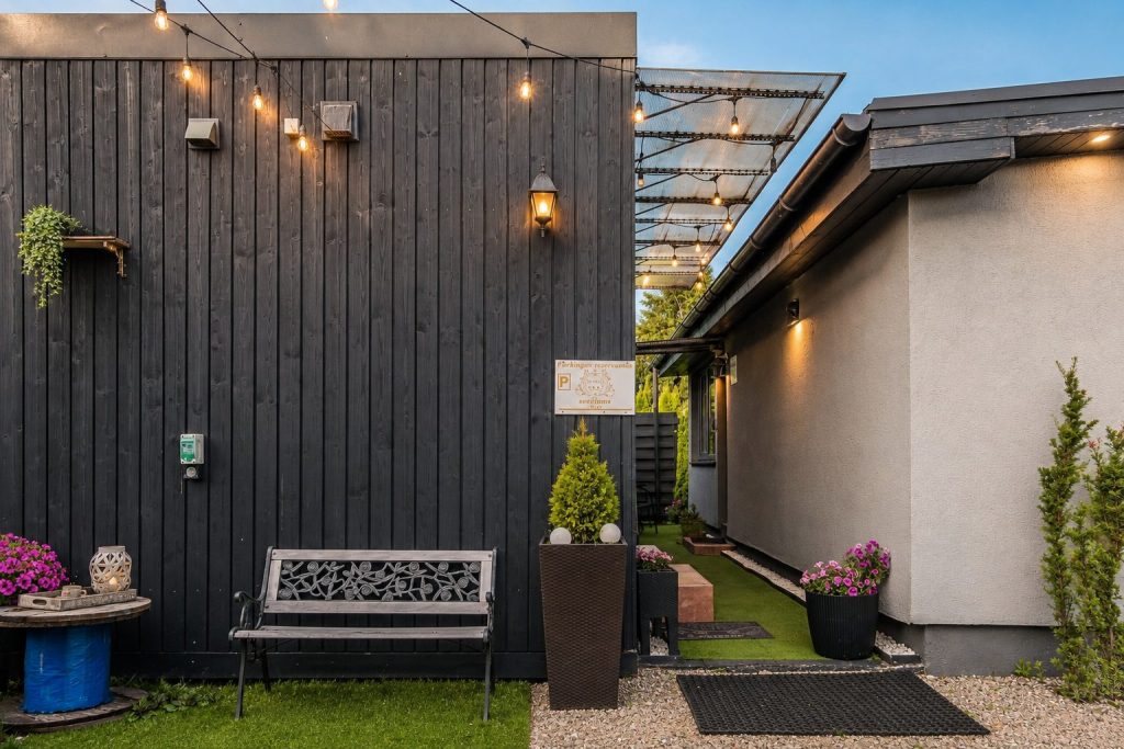 Apartamentų pastatas vakare su apšvietimu ir suoliuku kieme